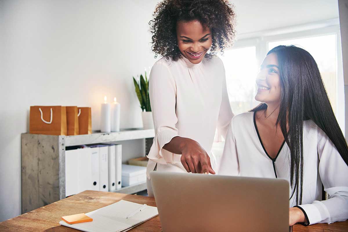 two digital marketing experts collaborating on a project at a modern office desk, using laptops and discussing strategies