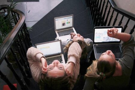 three digital marketers working on laptops looking upwards at the camara