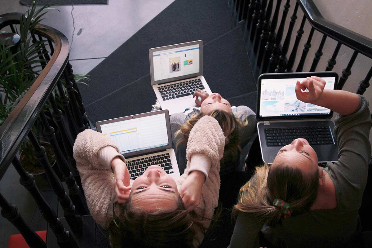 three digital marketers working on laptops looking upwards at the camara