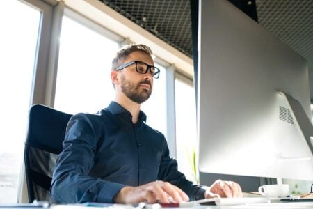 A PPC specialist managing online advertising campaigns on a computer at their workstation
